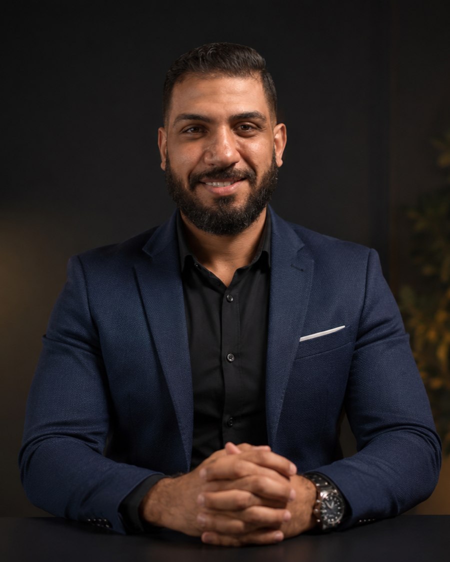 Eslam Galhoum wearing a navy suit, seated with his hands together